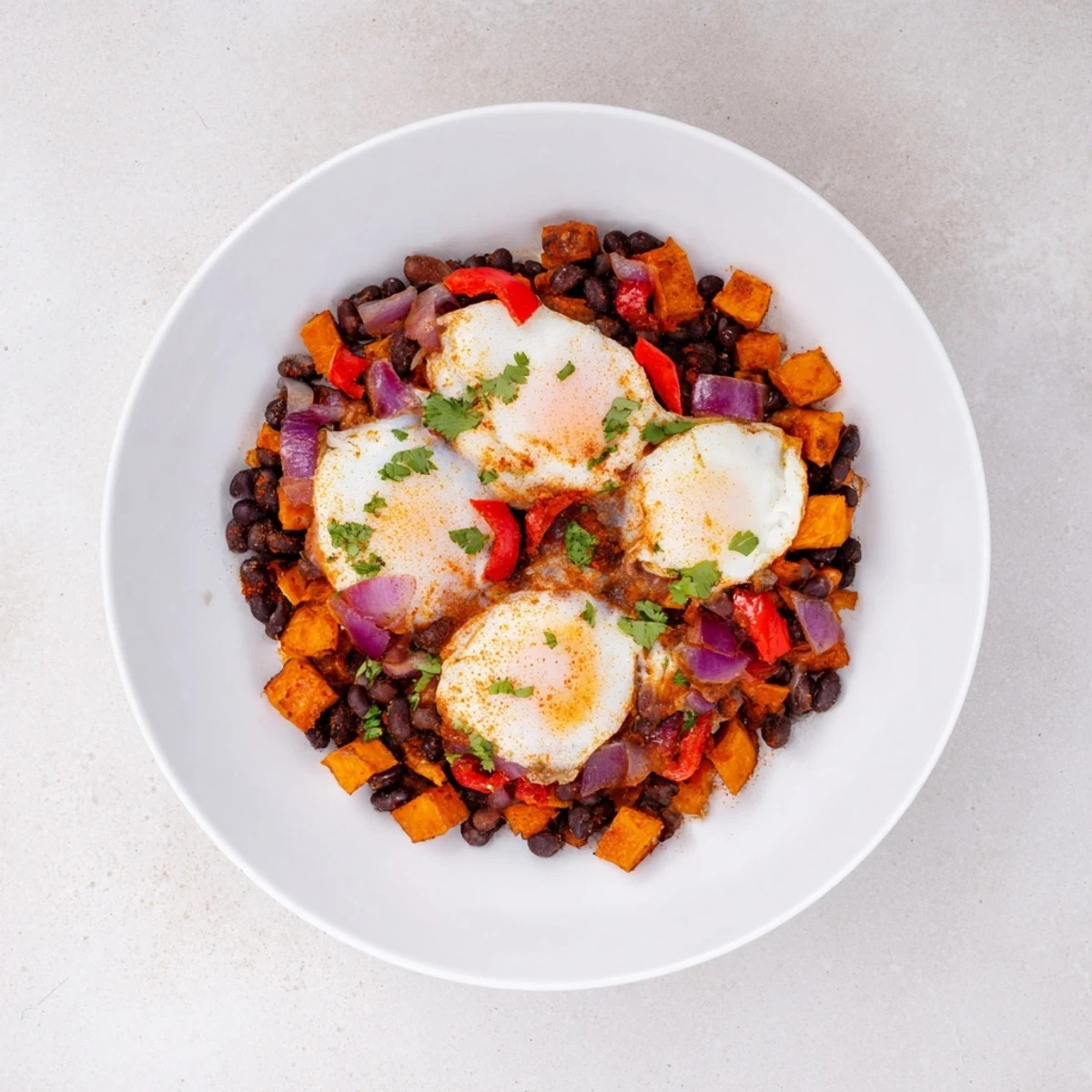 Golden-brown Sweet Potato & Black Bean Breakfast Hash topped with perfectly cooked sunny-side-up eggs.