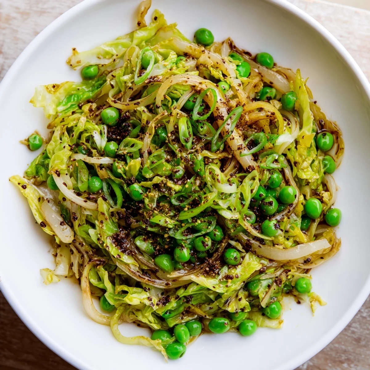Steaming cabbage stir-fry with garlic and peas, glazed in savory sauce, perfect as a quick side.