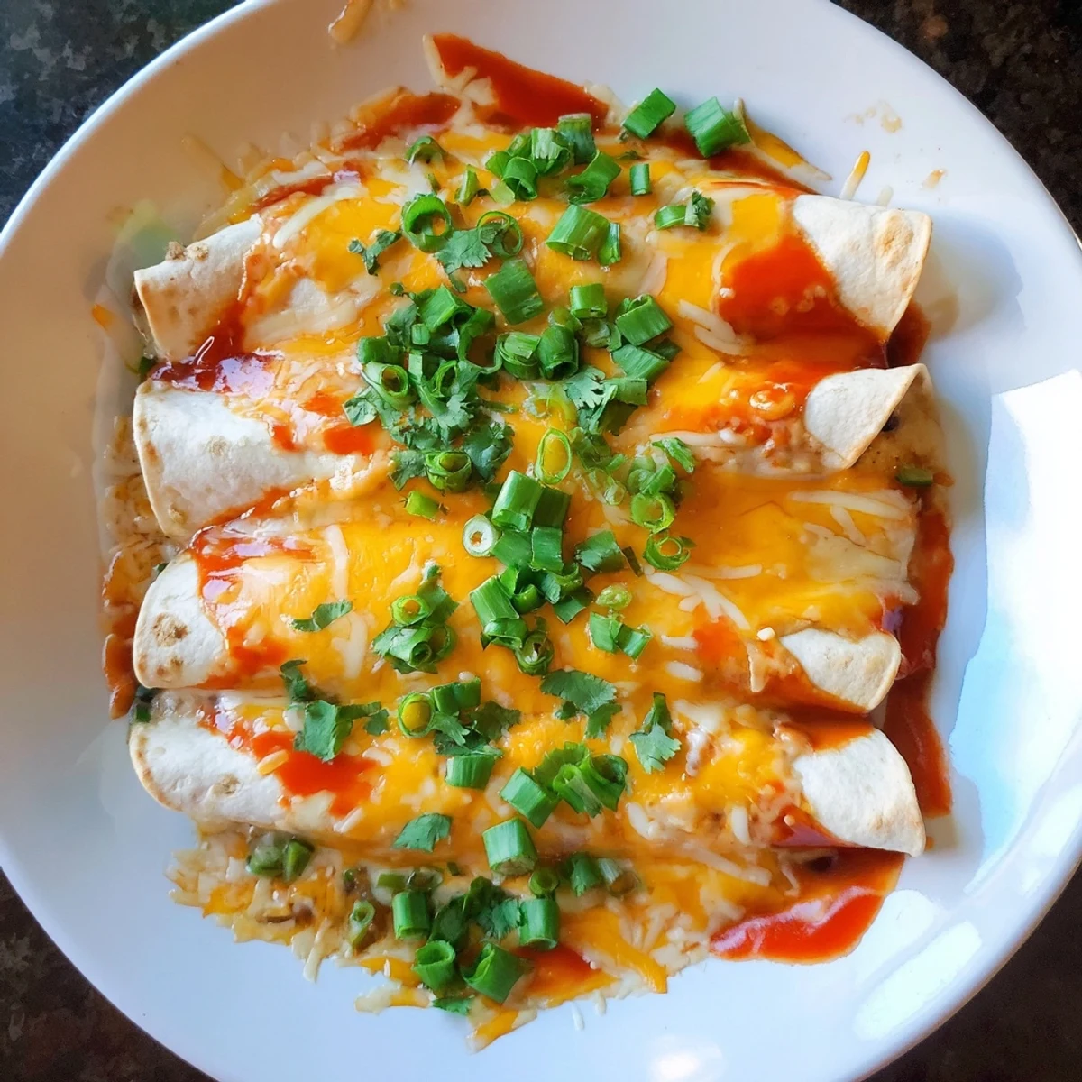 Golden, bubbling Cheesy Bean Enchiladas with melted cheddar cheese; a classic Mexican comfort food made easy.