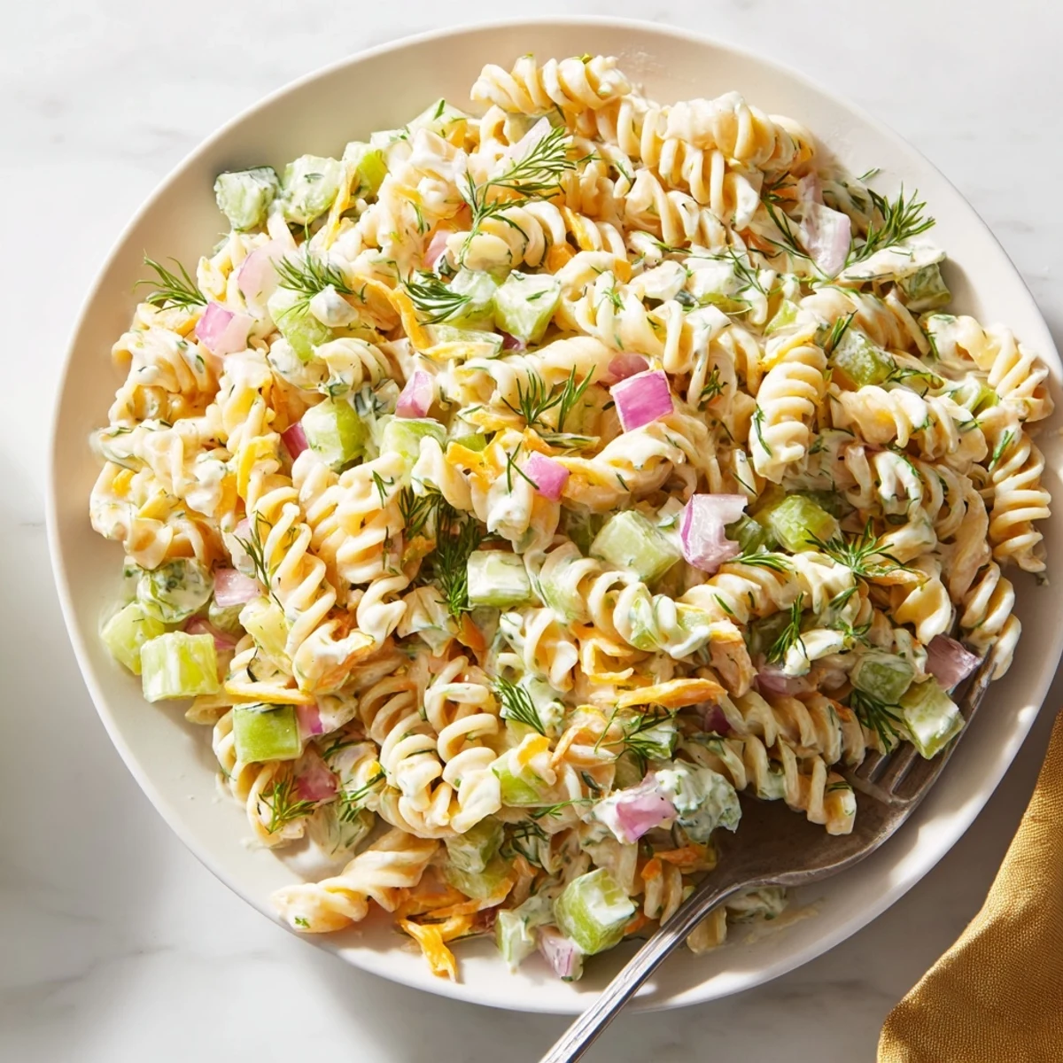 Cool Dill Pickle Pasta Salad showcasing the vibrant colors of pickles, red onion, and herbs.
