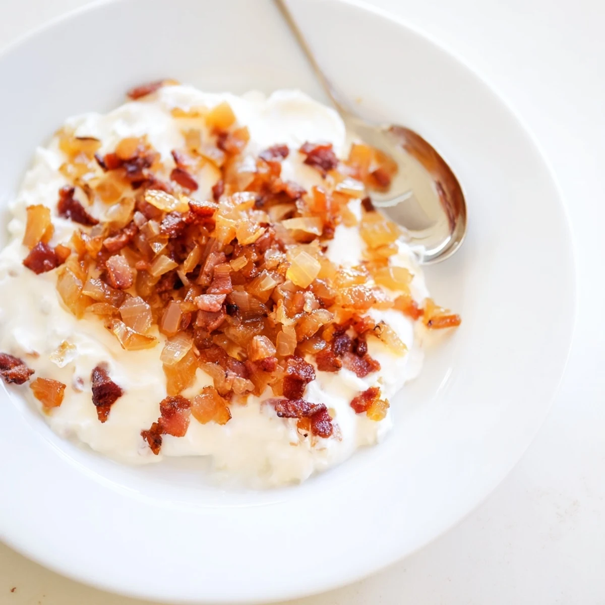 Brown, bubbling Caramelized Onion and Bacon Dip, served with crunchy potato chips for scooping.