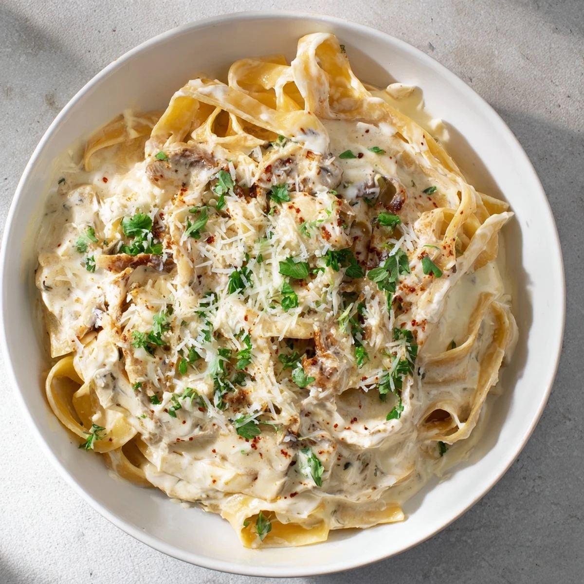 Steaming Skinny Alfredo Garlic Parmesan Snowy Pasta, a delicious lighter Italian main course, ready to serve with parsley.