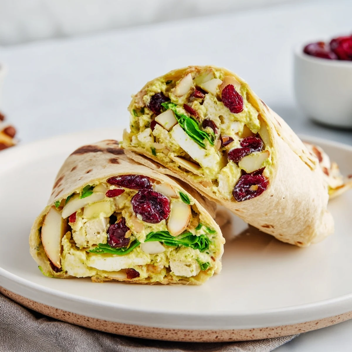 A vibrant Cranberry Goat Cheese & Walnut Holiday Wrap, showing a delicious, layered filling ready to eat.
