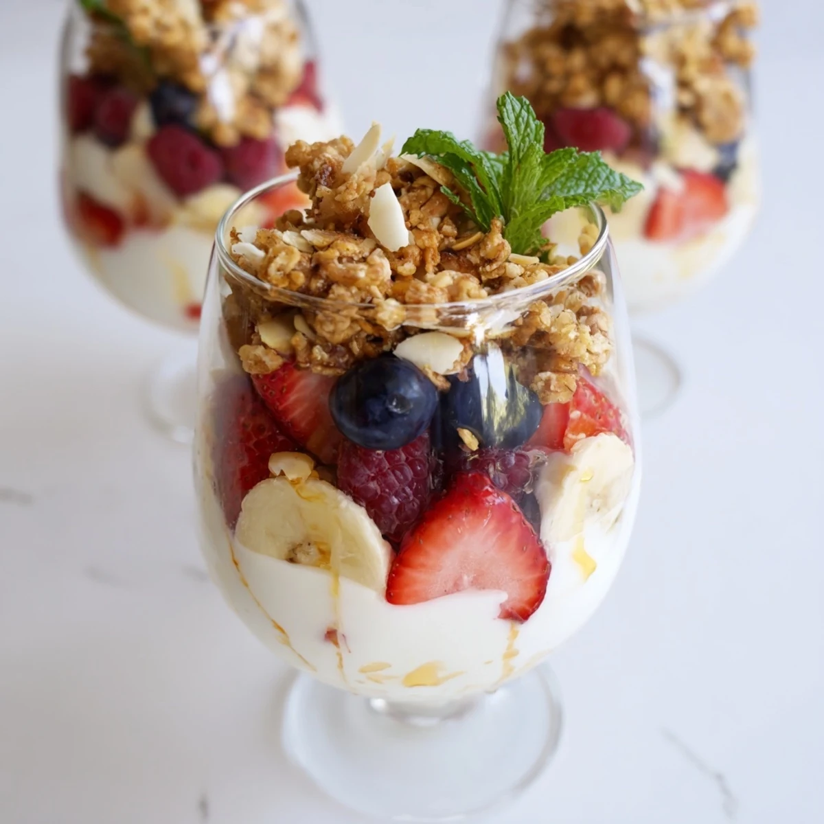 See this yogurt and granola parfait arranged in a tall glass, bursting with fresh, vibrant fruit.