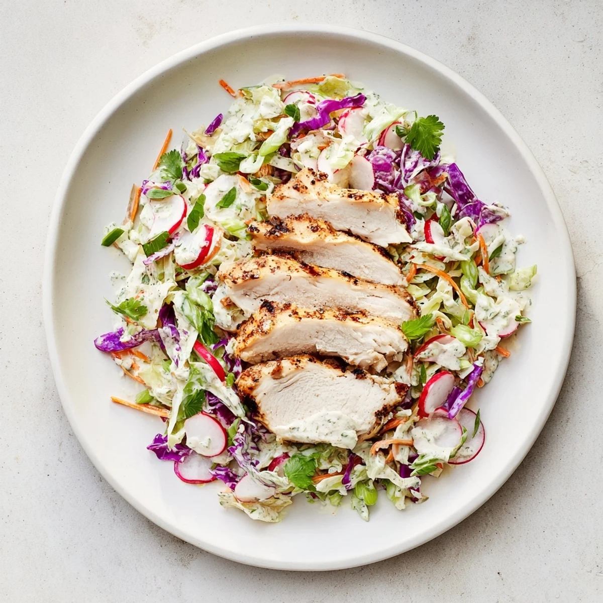 Juicy grilled chicken tops a colorful Green Goddess Cabbage Slaw, a refreshing American main dish.