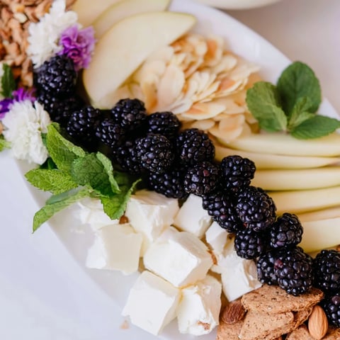Appetizing Yin-Yang Balance cheese board: blackberries, goat cheese, grapes, and crackers ready to enjoy.