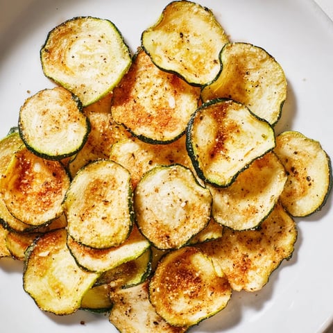 Golden, crispy zucchini chips, perfectly seasoned and ready to enjoy as a flavorful, crunchy snack.