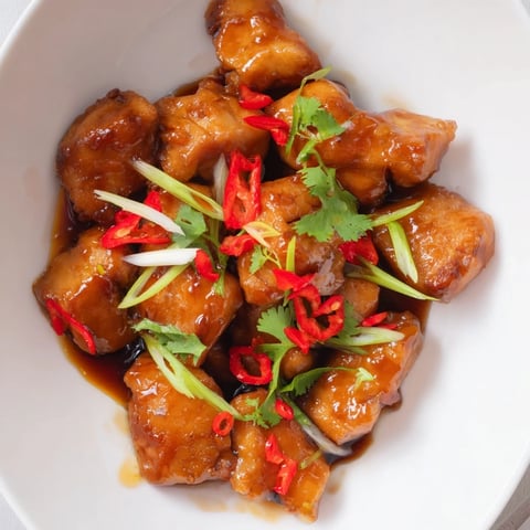 Aromatic Vietnamese Caramel Chicken with glossy sauce, garnished with fresh herbs and scallions.