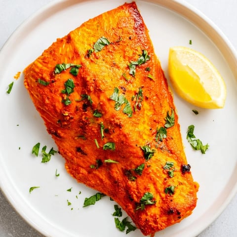 Vibrant Indian Tikka Salmon, beautifully roasted until flaky; a flavorful main dish with fresh herbs.