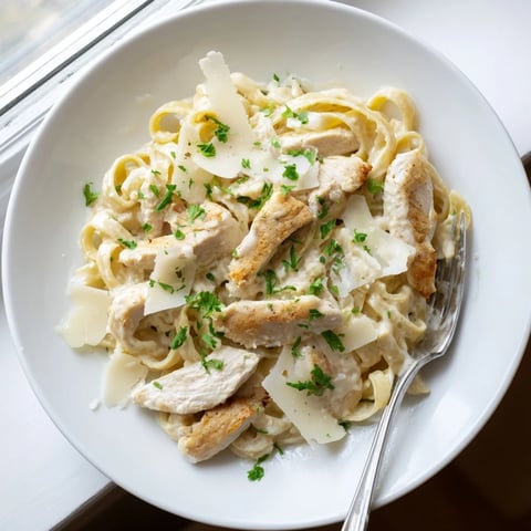 Creamy Skillet Chicken Alfredo with tender chicken strips and perfectly coated pasta, garnished with fresh parsley.
