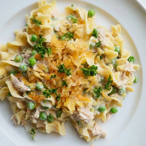 Golden, baked tuna noodle casserole glistens with creamy sauce, fresh herbs, and a crunchy topping.