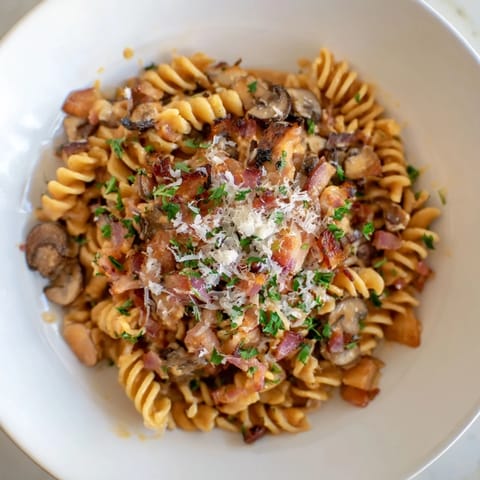 Golden, crispy bacon bits topping the flavorful fusilli with bacon, onions, and mushrooms dish.