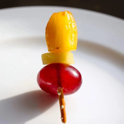 Vivid Christmas Light Fruit Skewers showcase ripe grapes, strawberries, and pineapple, perfect for a cheerful snack.