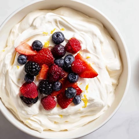 A gorgeous bowl of Fluffy Cream Cheese Fruit Dip surrounded by colorful, ripe, juicy berries.