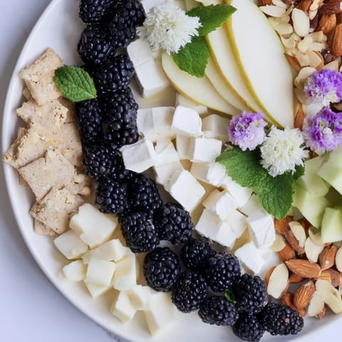 A beautiful Yin-Yang Balance appetizer board with dark plums, blue cheese, and roasted nuts offers varied tastes.