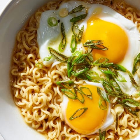 This upgraded instant ramen with egg looks delicious, featuring soft noodles and vibrant scallions.