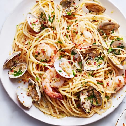 A close-up view of flavorful Seafood Pasta Aglio e Olio, garnished with fresh parsley and lemon wedges.