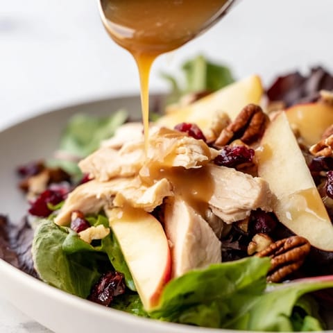 Hearty Caramel Apple Chicken Salad served on a platter, featuring feta cheese, red onion, candied pecans, and a glossy caramel dressing.