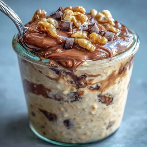 Two jars of Chunky Monkey Protein Overnight Oats topped with sliced bananas and chocolate chips ready to serve for breakfast. 