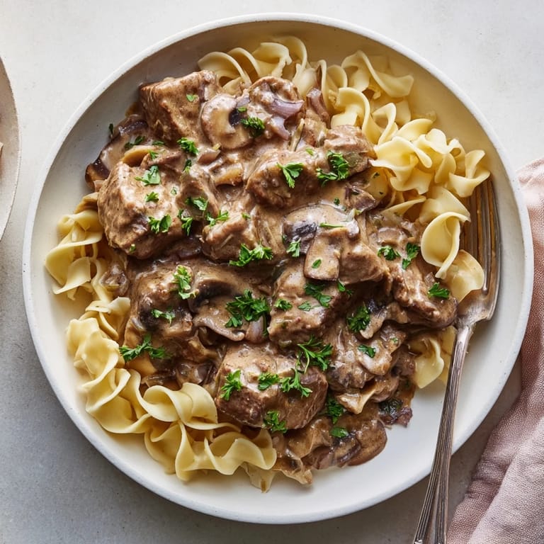 Creamy mushroom sauce enveloping beef in slow cooker beef stroganoff, served with mashed potatoes.  