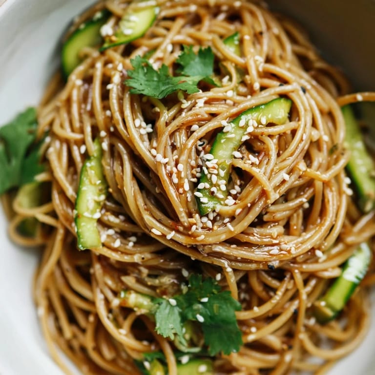 This spicy sesame noodle salad is garnished with toasted sesame seeds and sliced spring onions for vibrant color.