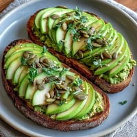 Avocado and Green Apple Breakfast Toast with Pumpkin Seeds: a vibrant, creamy avocado spread topped with crisp green apple slices and crunchy pepitas.